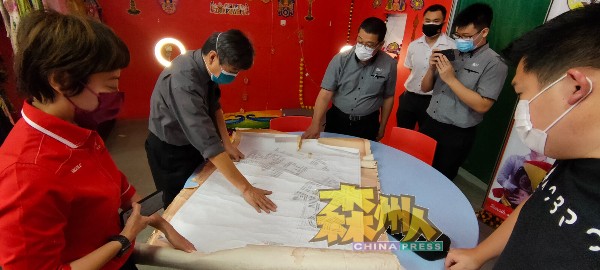 刘志坚（左2）向陈丽群（左）展示2008年的总计划图测，右为张国耀。