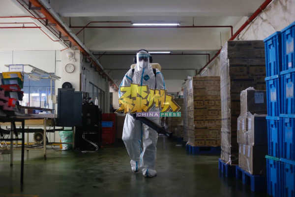 穿著防護服的消拯員進入頻頻傳出員工確診的工廠內進行消毒。