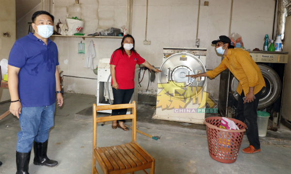 洗衣店东主帕威沙马（右）向吴健南（左起）与何彩思，讲述水灾的水位高度及洗衣器材的损坏情况。