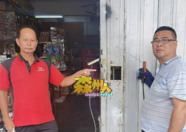 钟先生（右）雇人加固门锁防盗的设施，左为陈顺彬。