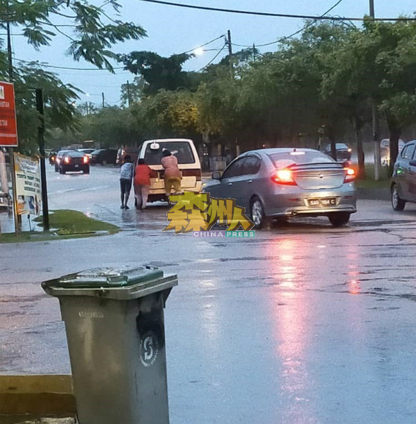 好心的民众冒着大雨协助车主，把抛锚的车辆推往安全处等待救援。