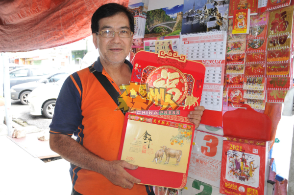 吴国福展示其中一款印有生肖的日历。
