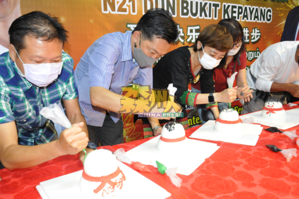 黄焯贤（左起）、谢琪清、陈丽群及何明和一同进行雪人蛋糕装饰。