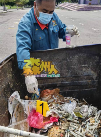 森州环境局官员小心翼翼，从垃圾桶内抽取样本。