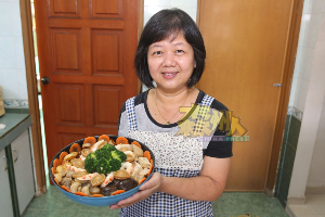 素厨娘黄燕玲正在叠着素盆菜的各菜肴，盆菜叠高高具有好意头的含意。