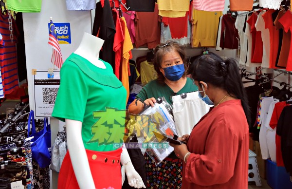 服装小贩向友族消费者介绍服装，以争取客源。