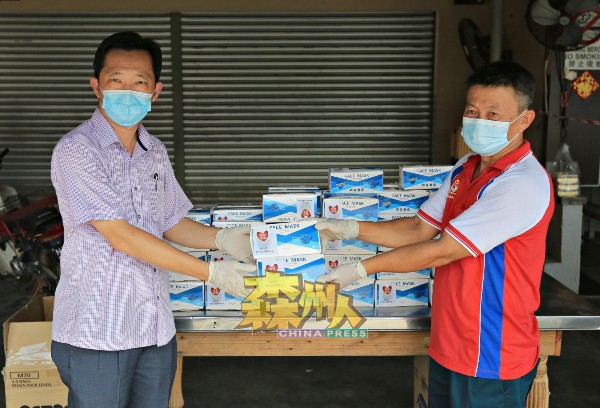 谢琪清（左）为受疫情波及的芙蓉拉务八哩新村送暖，移交200盒口罩予李恒华村长。