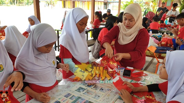 家长与学生用红包袋，学习制作新年装饰。