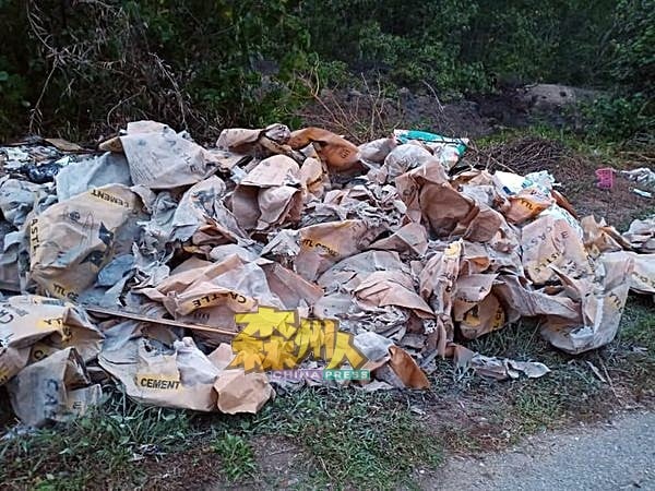 大量的混凝土包装袋随意丢弃在瓜拉芦骨路边。