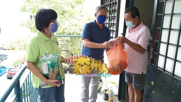 前巴音村长黄六妹（左起）陪同赖振光派发援助品给面临断粮的组屋居民。