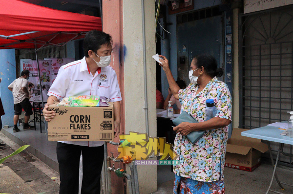 在派发食物篮的活动中，谢琪清（左）全程在场，并协助一些长者提取食物篮。