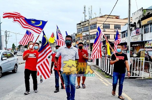 阿鲁古马（中）率领村委会成员在文丁市镇张挂国旗，为营造国庆气氛作出最后冲刺。