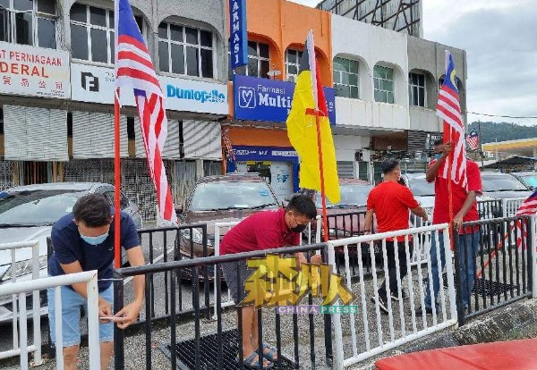 志工团在候车站桥樑张挂国旗州旗，让市民在疫情当下，也能感受到国庆氛围。