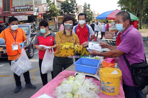 陈丽群（左3）分派口罩和消毒液予早市小贩，左4为谢琪清。