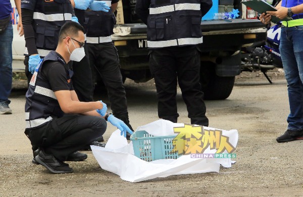 鉴证组警员把黏糊糊物状的婴尸放入篮子里，方便包裹及携带。