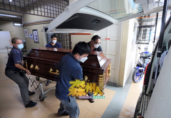 殡葬业者把装有死者何征贤遗体的棺木抬上棺车，以送往真光道堂。