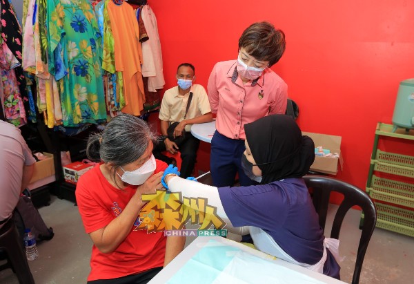 陈丽群（站者）巡视一名华裔妇女接种疫苗。