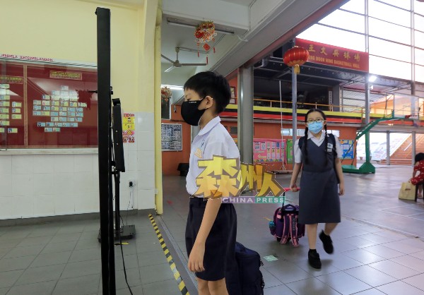 返校上课的学生，在进入校舍前测量体温。