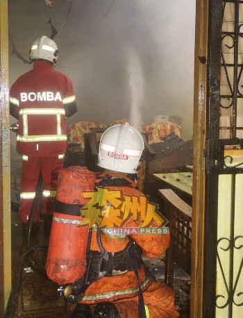 消拯员进入客厅灌水，阻止火势蔓延至隔壁民房。