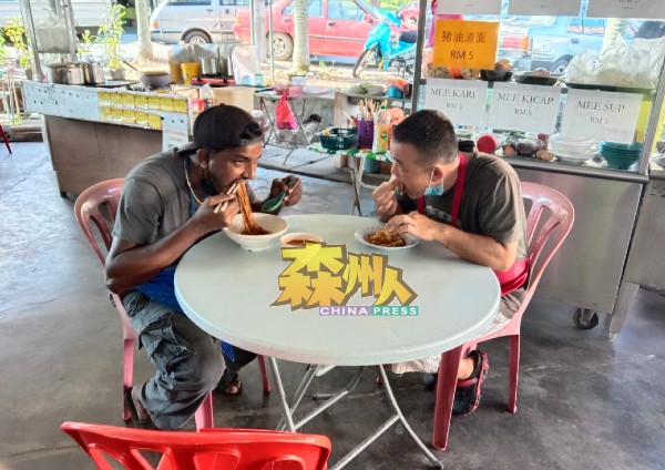 摩根（左）用华裔的筷子吃面，邓丹平用手抓印度煎饼沾羊肉咖哩吃，其乐融融。