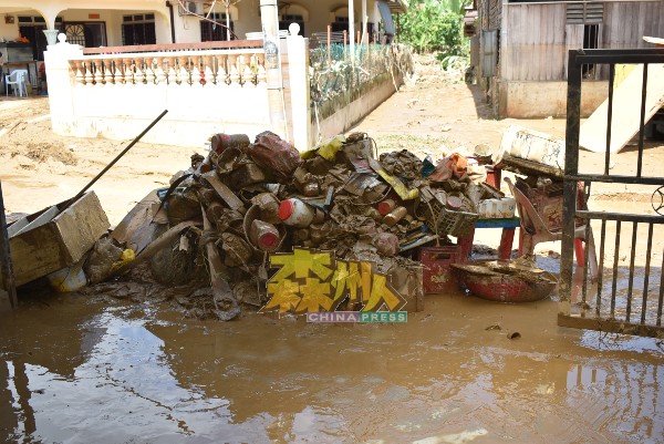 灾黎在清理住家时，清理出一大堆随洪水飘来的垃圾。