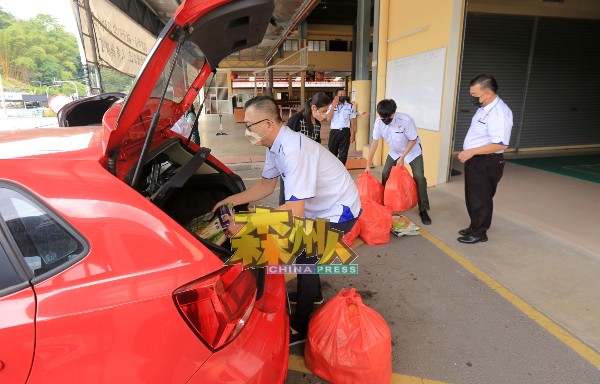 马来西亚善心组织理事出钱出力，协助校长搬运各自申请的12份食物篮上车，以派发给有需要的清寒生。