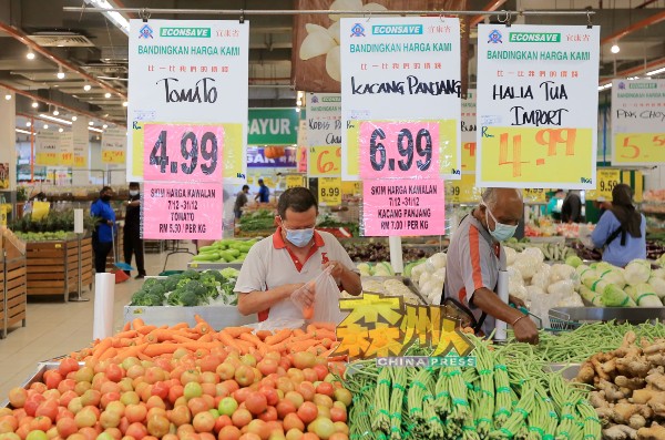 消费者根据超市的标价及统制品顶价标籤，选购蔬菜。