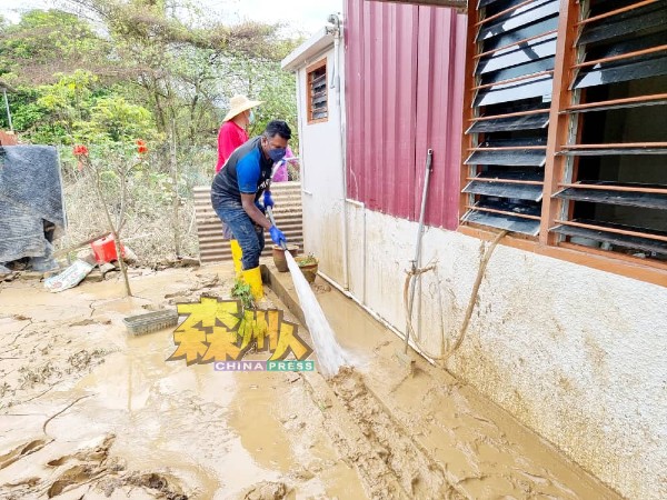 阿鲁古玛（前）与团队协助清理家园泥泞。