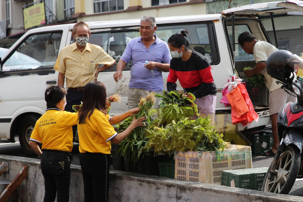 流动菜商看中“亚沙社区市集”带热买气，把菜车泊在服务中心附近卖菜。