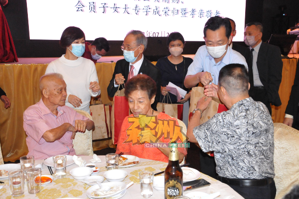 谢琪清（右）及陈怀国（中）派发礼袋予出席“梅江之夜”的年长会员。