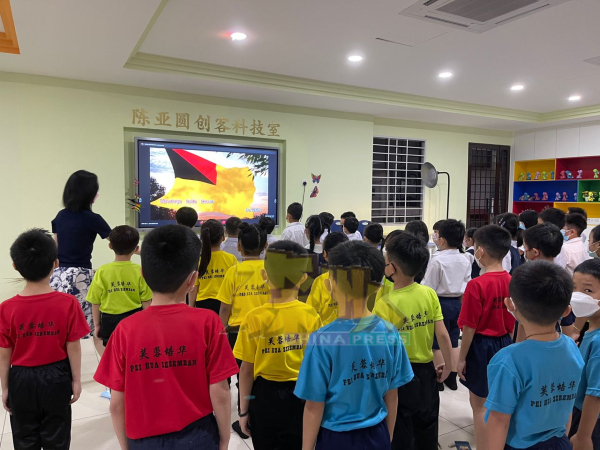 培华小学的一年级学生们在实验室进行周会，集体唱国歌和校歌。