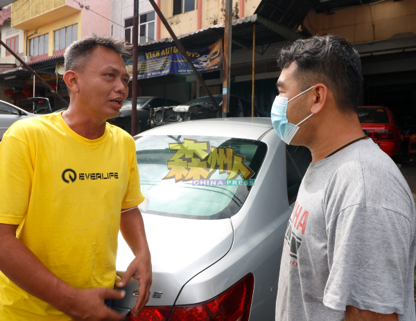 刘秋兴（左）要求维修点商家林健德配合，将停泊在新村泊车位已久的维修车移走。