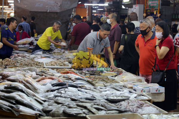 鱼摊小贩忙得不可开交，忙着处理顾客选购的海鲜。