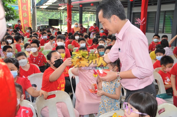 谢琪清（右）分派红包给三民小学学生。
