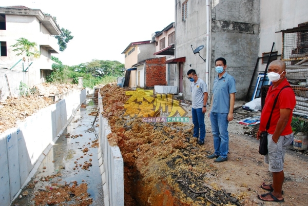 张聒翔（中）巡视马口东方花园的排水系统工程。