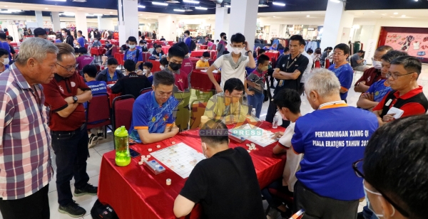 象棋国际大师沈毅豪（蓝衣坐者），以及坐在他隔壁的中国籍象棋国际大师黎德志，在最后一局与对手交战，吸引众人围观。