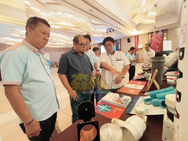邓光洺（左）陪同水务公司总经理阿都拉查，参观各种展示的水喉产品。