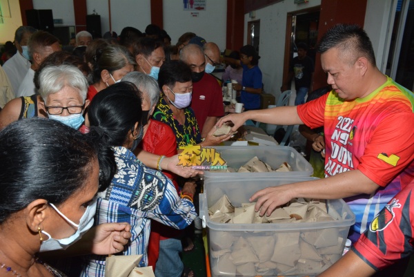 吴金财（右）忙着派发食物，让民众品尝道地美食。 