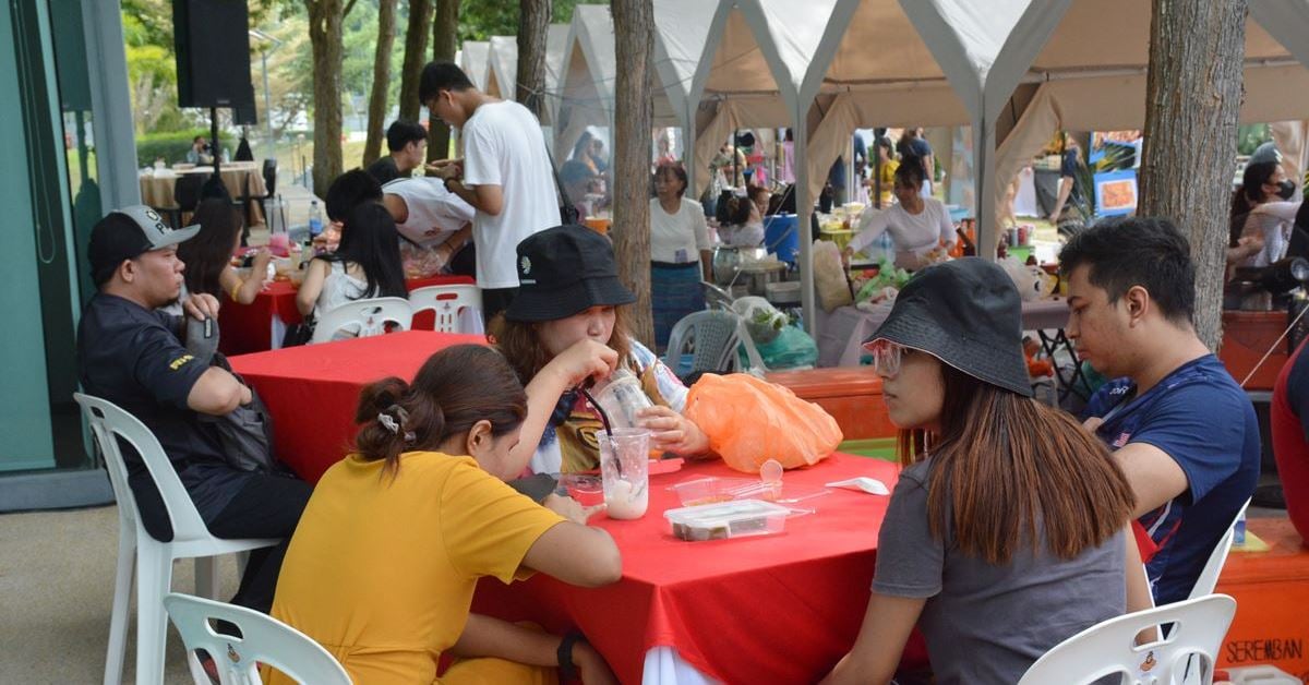 许多民众购买泰国美食后，在摊位旁的桌位享用。