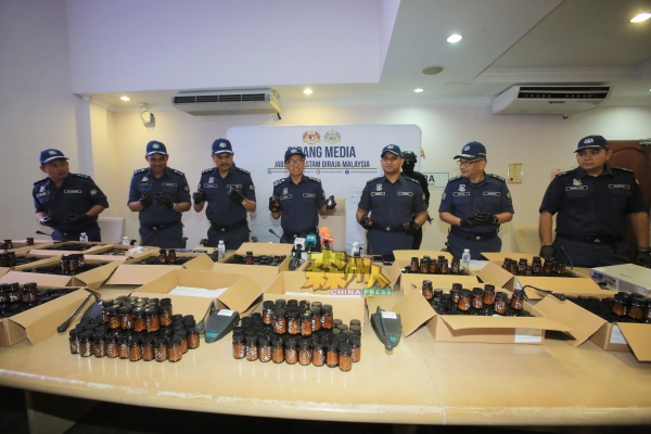 扎祖里(左4)与关税局肃毒组官员展示起获的995瓶装有可卡因胶囊的“保健品”瓶。
