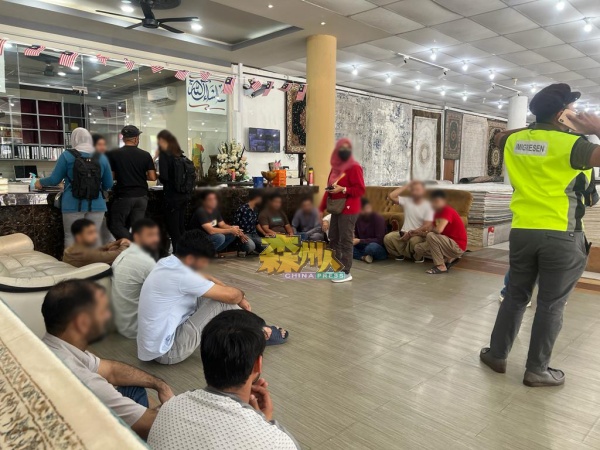 移民局官员在一间地毯店逮捕非法入境者。