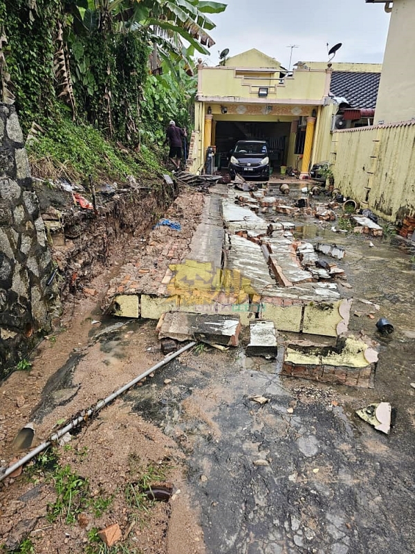 山坡下民宅长达30尺高5尺半的围墙，早前疑地基受损，如今不堪连绵豪雨冲刷，应声倒下。