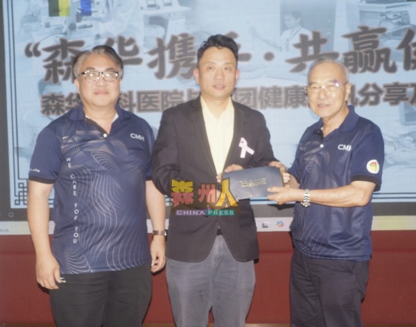 韩春锦（右）颁赠礼物给黄仕豪医生，左为邱德隆。